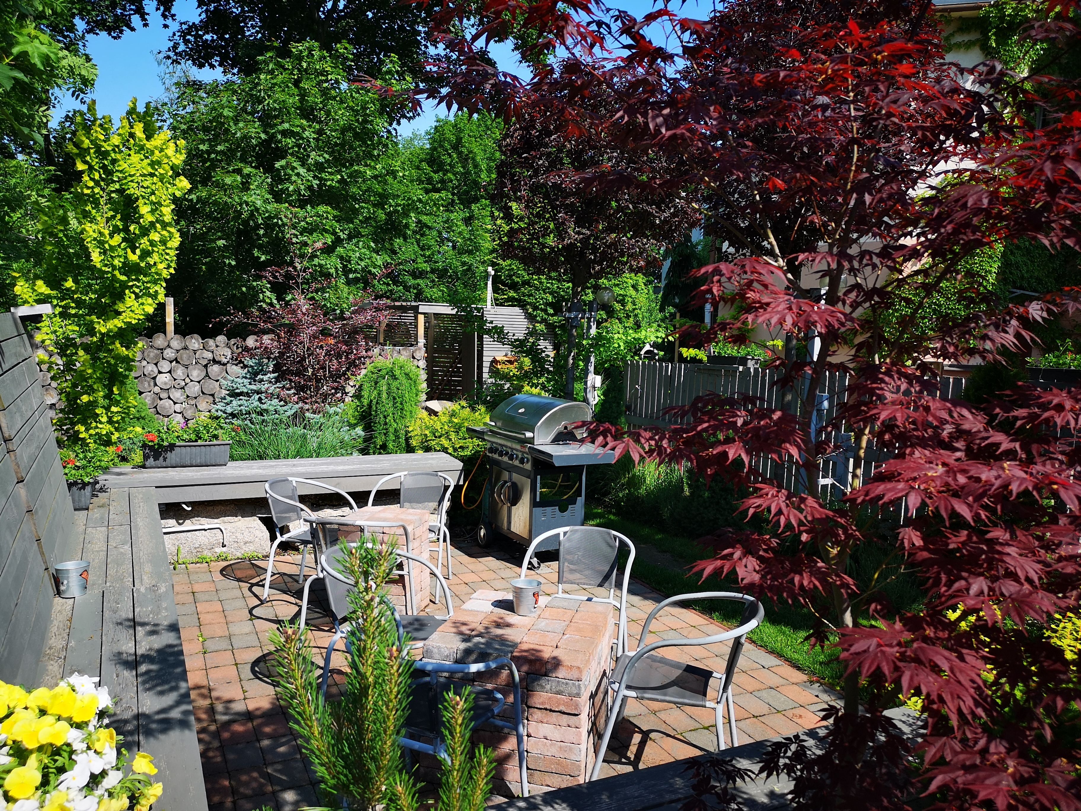 A patio with a grill, outdoor seating, and a stone wall.