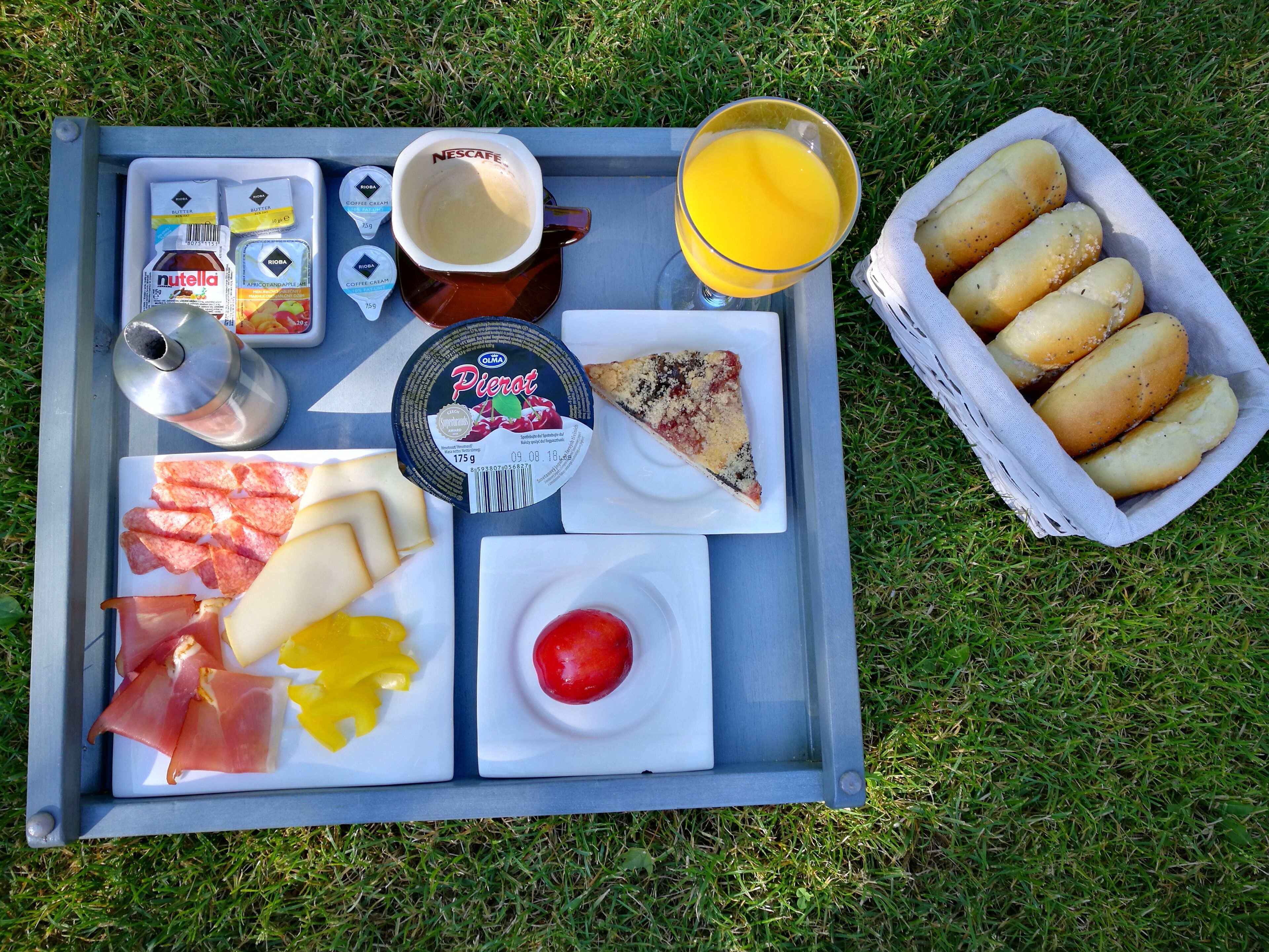 Ein Tablett mit verschiedenen Speisen, darunter Pizza, Käse, Prosciutto, einer Tomate und Brötchen.