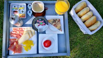 Ein Tablett mit verschiedenen Speisen, darunter Pizza, Käse, Prosciutto, einer Tomate und Brötchen.