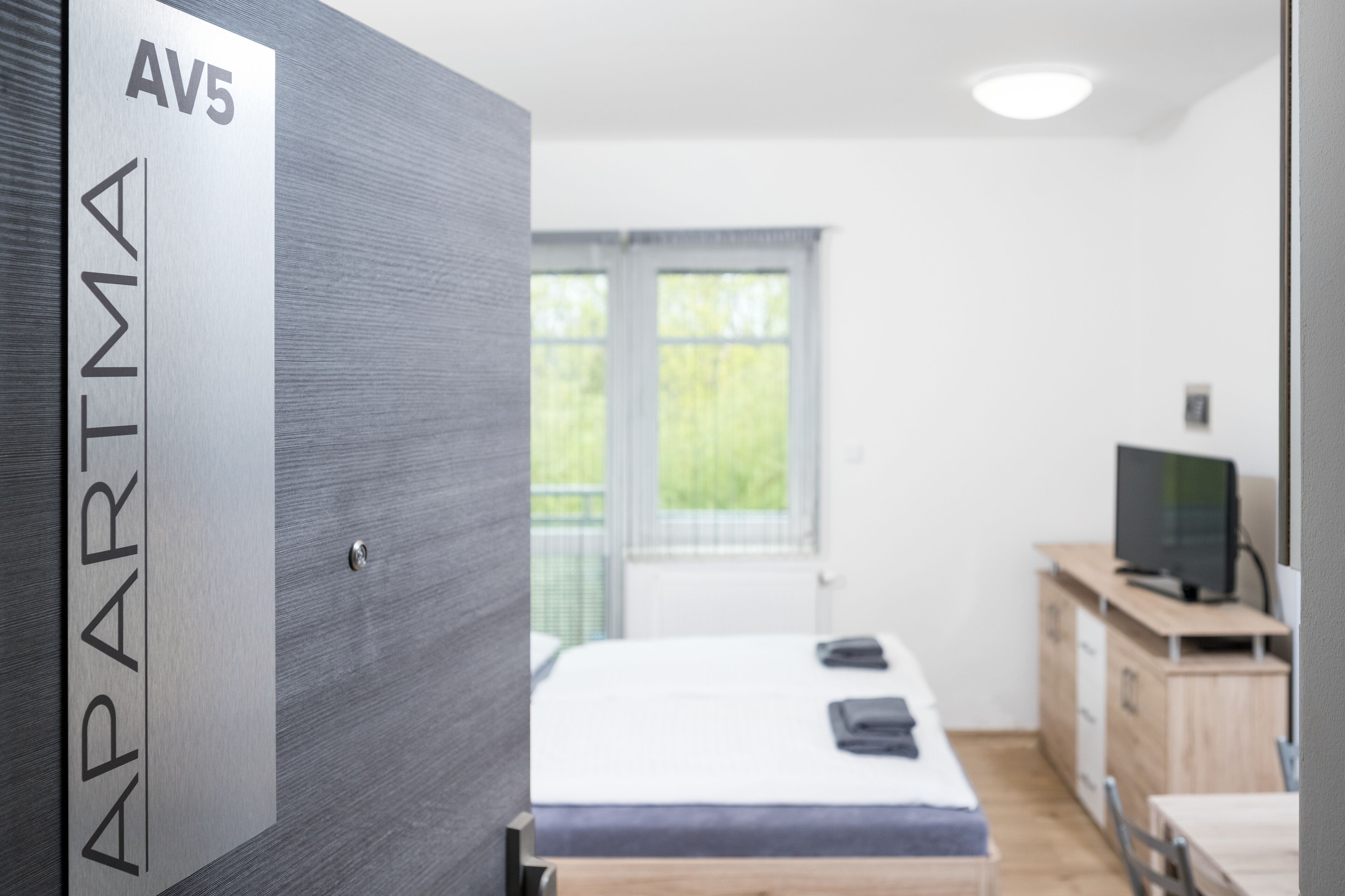 A modern bedroom with a bed, a TV, and a desk.