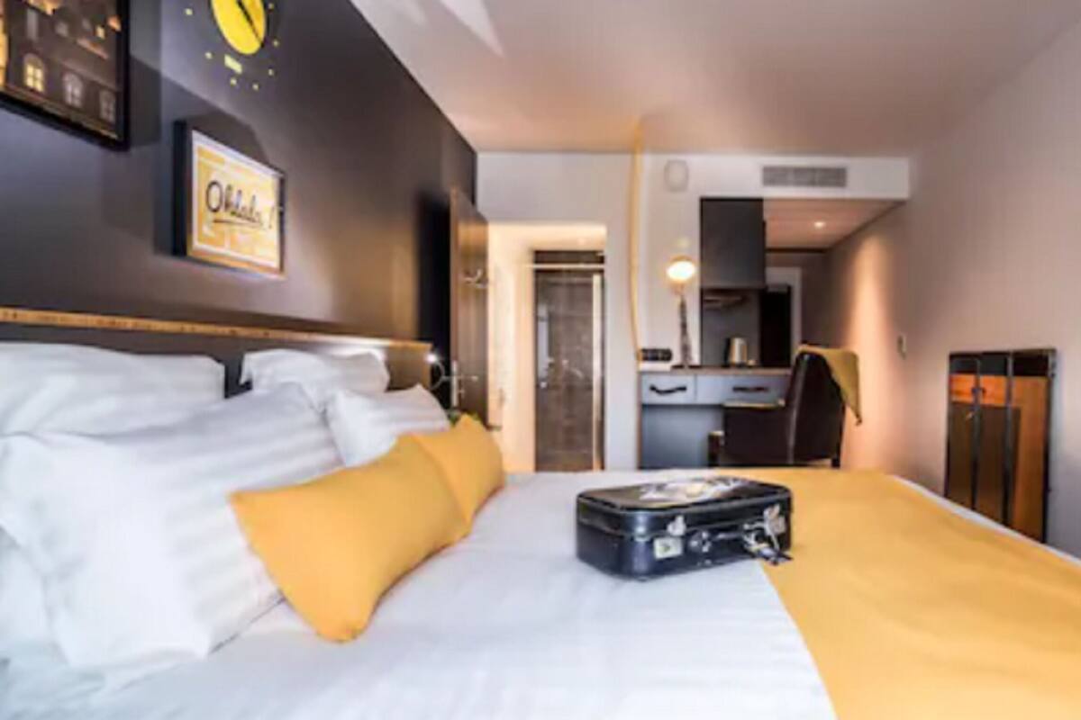 A hotel room with a bed, a suitcase, a desk, and a chair.