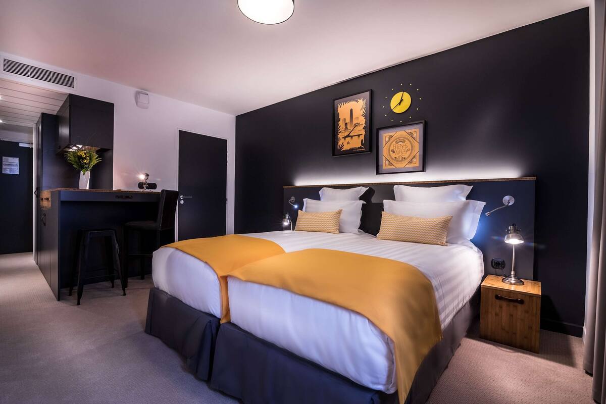 A modern bedroom with a large bed, bedside tables, a desk, and a chair.