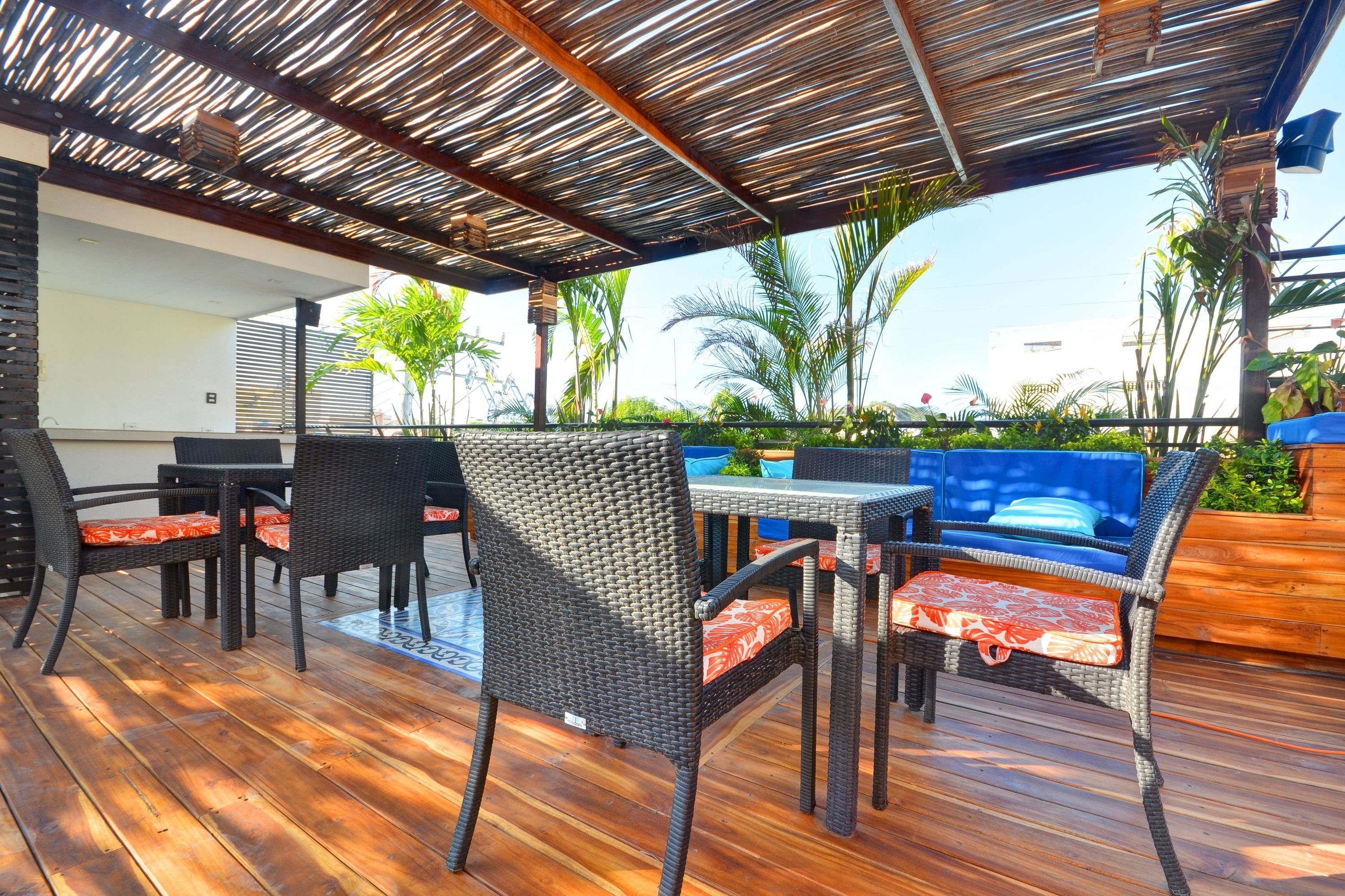 Un patio exterior con mobiliario de mimbre, una terraza de madera y un techo de paja.