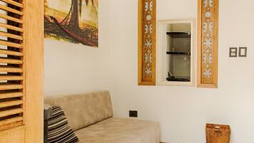 A living room with a beige sofa, a wooden sideboard, a painting, and a mirror with decorative wooden frames.