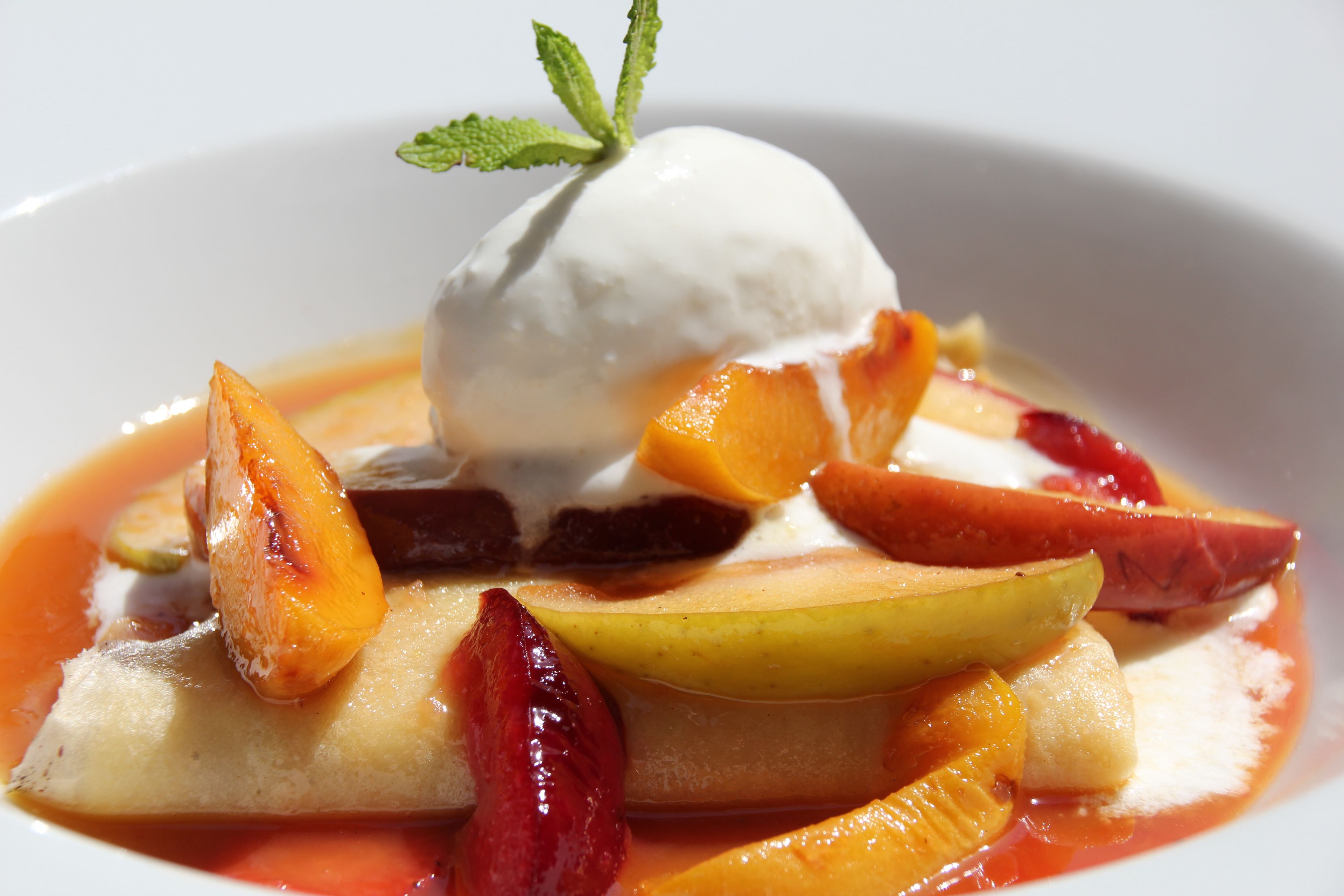 A dessert with fruit and a scoop of ice cream on a plate.