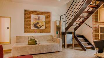 Una sala de estar con sofá, una escalera y un cuadro en la pared.