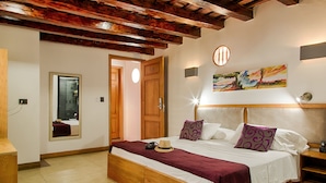 Un dormitorio con una cama de madera, un espejo, una puerta y un cuadro en la pared.