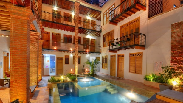 Un patio de varios niveles con piscina, balcones de madera y un muro de ladrillo.