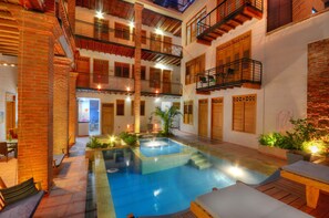 A multi-level courtyard with a swimming pool, wooden balconies, and a brick wall. - Hotel Boutique Casa Carolina Santa Marta (Santa Marta)