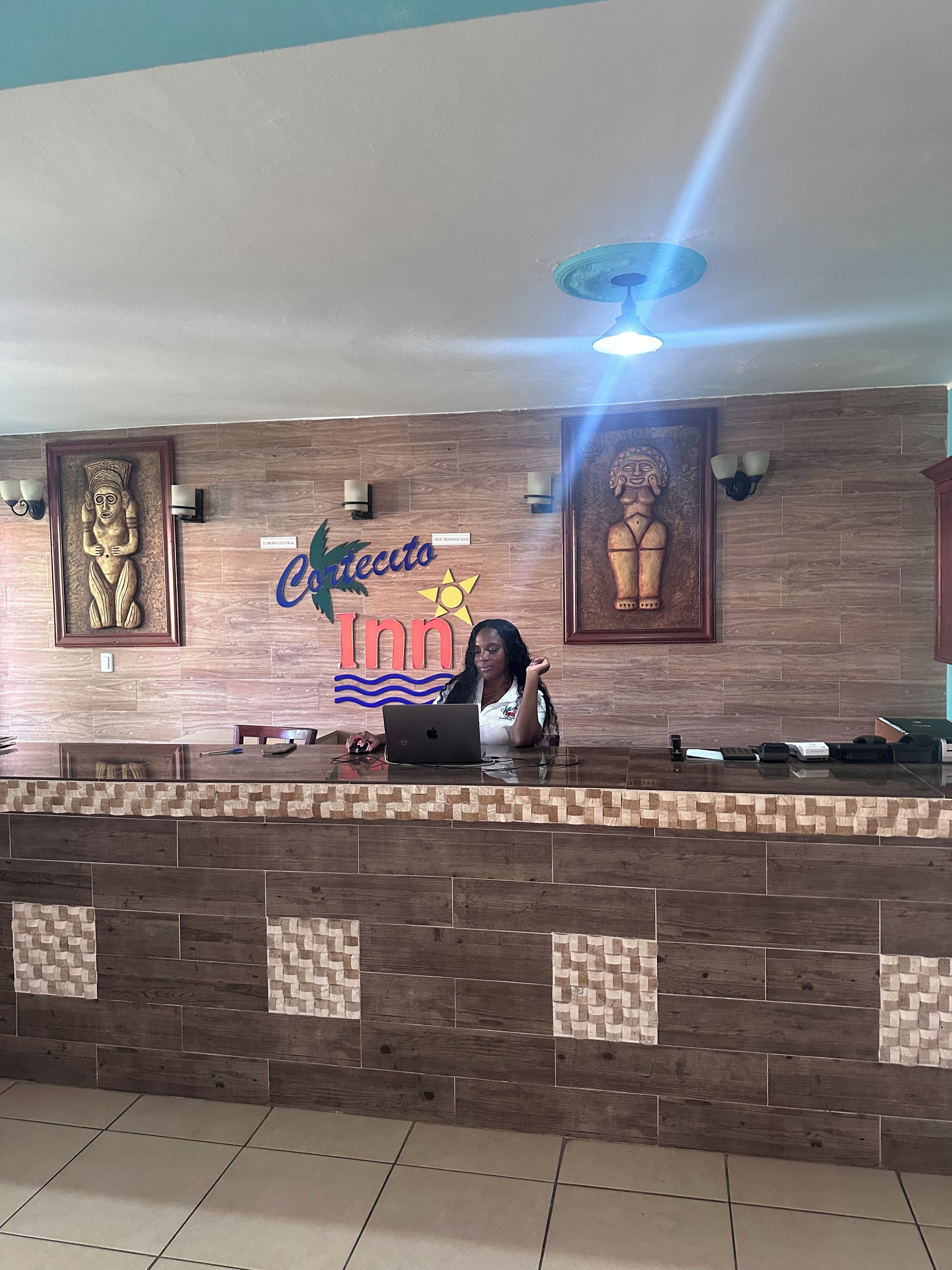 A reception desk with a laptop, framed artwork, and a sign for 'Cecito Inn.'