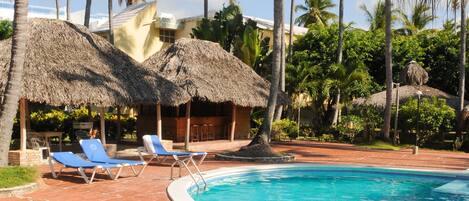 A swimming pool with clear blue water, surrounded by lounge chairs and palm trees.