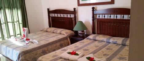 Dos camas individuales con ropa de cama floral, una lámpara de mesa verde y un cuadro en la pared.