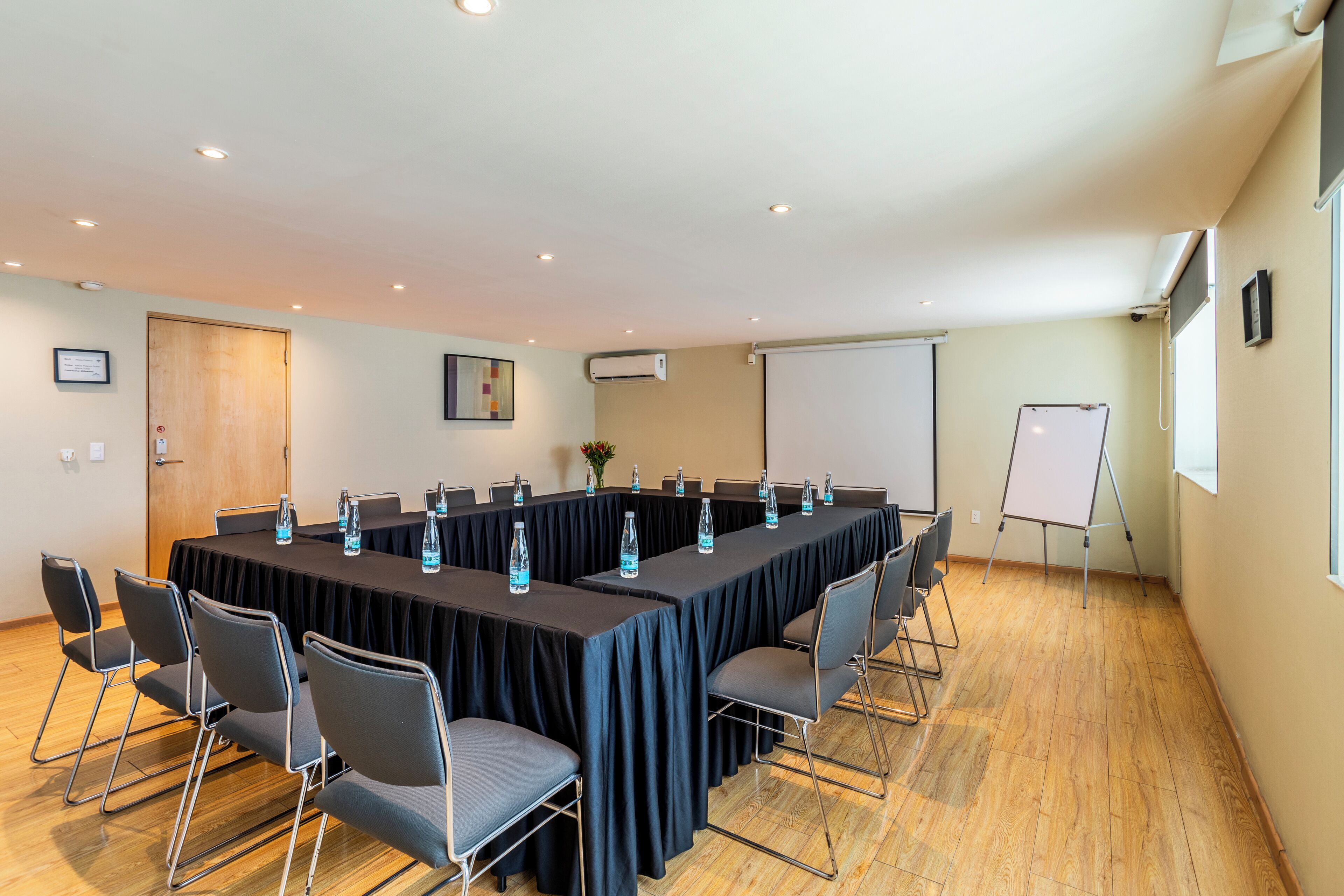 Une salle de conférence avec une longue table, des chaises et un tableau blanc.
