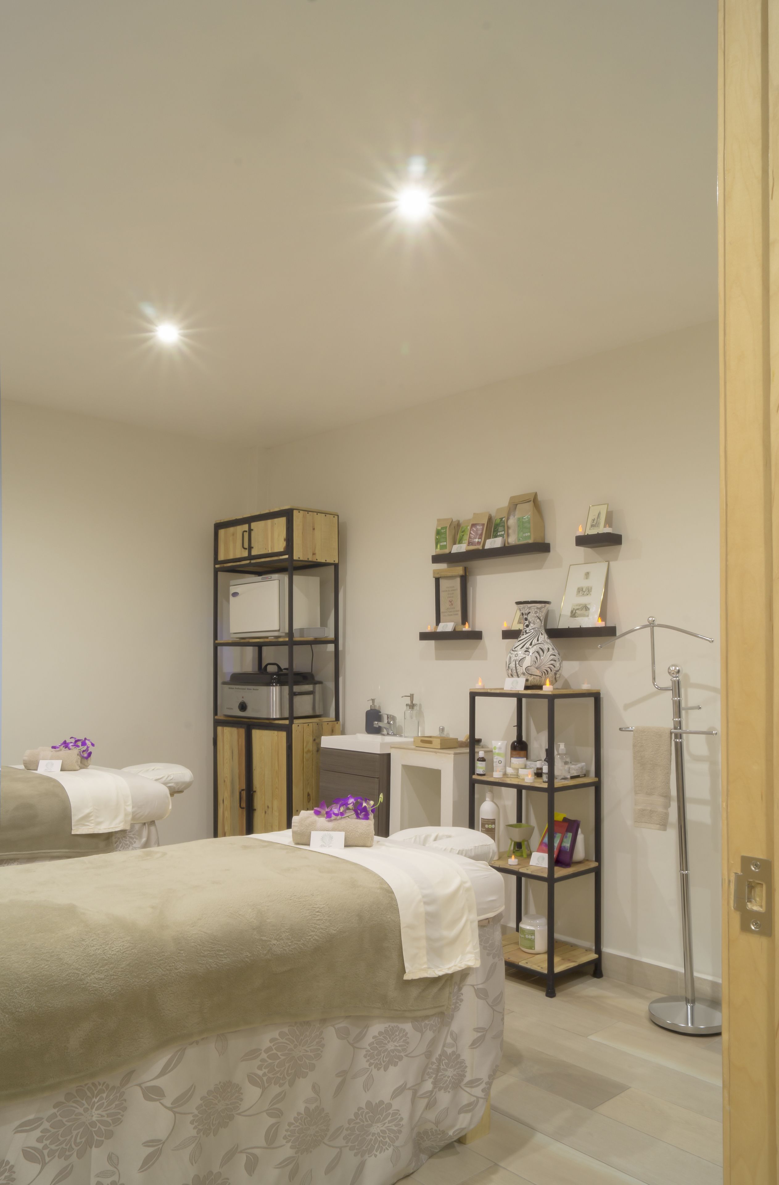 A hotel room with two beds, a vanity with shelves, and a desk.