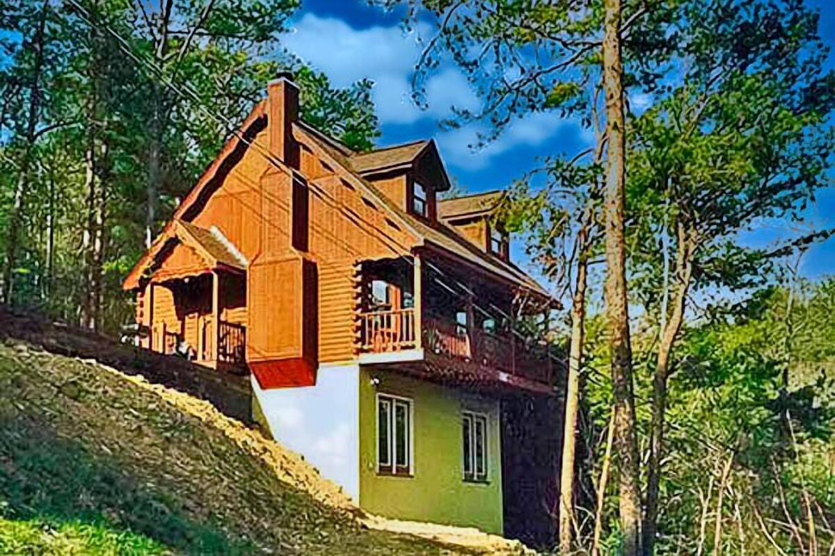 Una casa de madera con balcón, ubicada en un área boscosa.