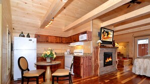 Un interior de cabaña acogedor con cocina, comedor y chimenea.