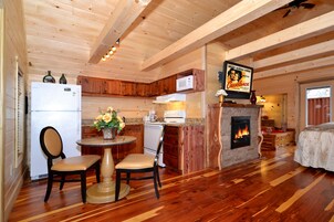 Un interior de cabaña acogedor con cocina, comedor y chimenea.