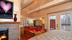 Un dormitorio amplio con una cama grande, chimenea y techo de madera.