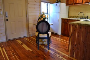A wooden interior with a dining area featuring a chair and a table, a white refrigerator, and a kitchen counter with a sink. - Honeymoon Hills Gatlinburg Cabin Rentals (Gatlinburg)