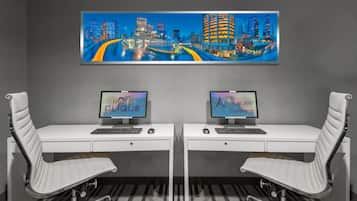 Habitación de hotel con dos escritorios, cada uno con una computadora y una silla.