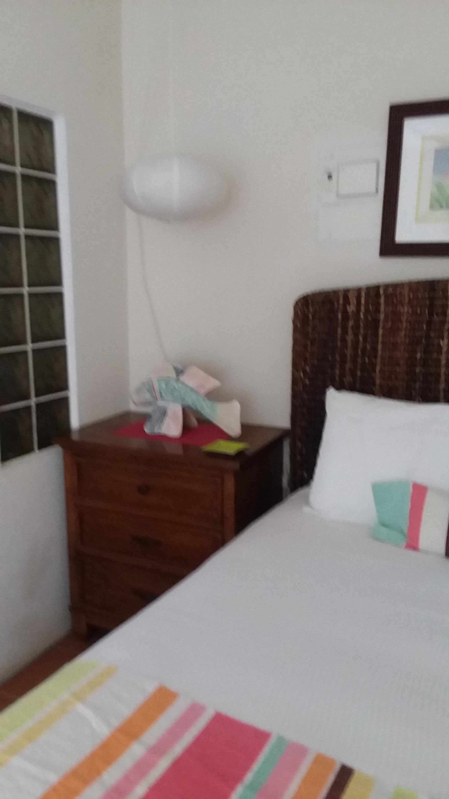 Un dormitorio con cama, mesita de noche, lámpara y ventana.