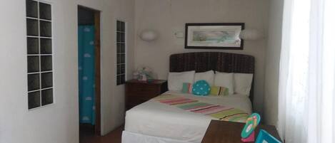 Ein Schlafzimmer mit Bett, Schreibtisch und Deckenventilator.