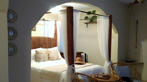 A bedroom with a canopy bed, a small table with chairs, and a ceiling fan. - Casa de Tortuga (Vieques)