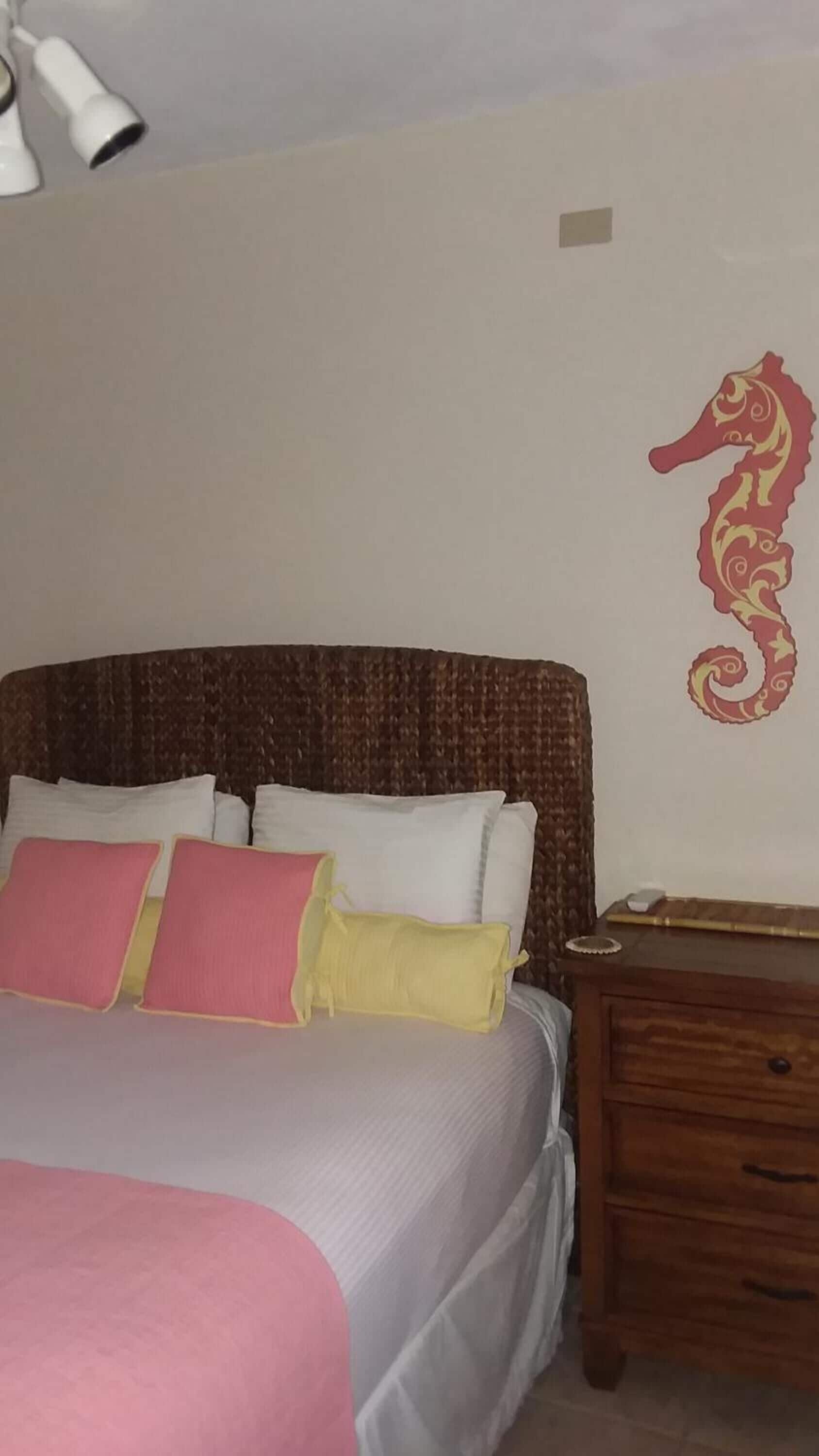 Une chambre à coucher avec un lit, des oreillers, une table de chevet et un élément décoratif mural.