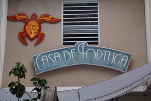 Une enseigne pour le « Casa de Portugal », ornée d’une tortue décorative et comportant une fenêtre avec des stores horizontaux.
