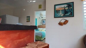 A kitchen area with a refrigerator, a bar counter, and a seating area with two stools. - Casa de Tortuga (Vieques)