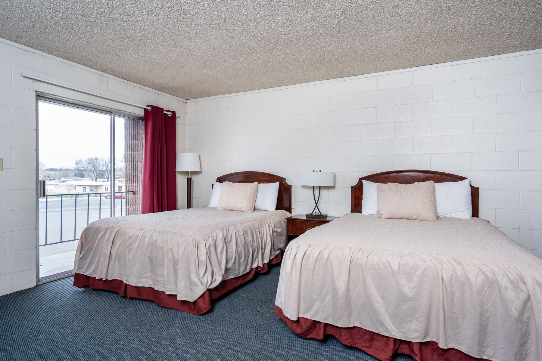 Quarto de hotel com duas camas, uma janela grande e vista para o exterior.