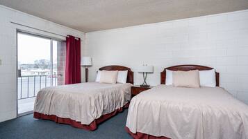 Quarto de hotel com duas camas, uma janela grande e vista para o exterior.