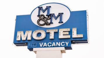 Een motelbord met 'M&M' en 'MOTEL' aanduiding, en een 'GEEN KAMERS BESCHIKBAAR' bericht.