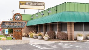 Un restaurante con toldo verde, un letrero y plantas en macetas.
