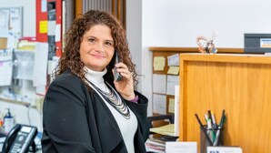 Una persona en un entorno de oficina, con un escritorio, teléfono y diversos útiles de oficina.