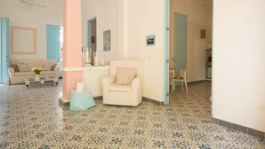 A room with a patterned floor, a sofa, a chair, and a small table with a vase of flowers. - La Casa del Patio Hotel Boutique by Xarm Hotels (Santa Marta)