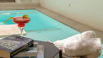 A poolside setting with a drink, a book, and a towel.