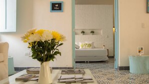 A room with a bed, a bedside table with a vase of flowers, and a magazine on the floor. - La Casa del Patio Hotel Boutique by Xarm Hotels (Santa Marta)