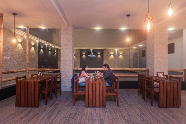 Un restaurant avec des meubles en bois, un mur en briques et des luminaires suspendus.