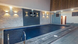 A swimming pool with a wooden deck, a stone wall with a logo, and a wooden ceiling. - Galapagos Native (Puerto Ayora)