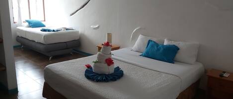 A hotel room with a large bed, a smaller sofa bed, a bedside table, and a nightstand.