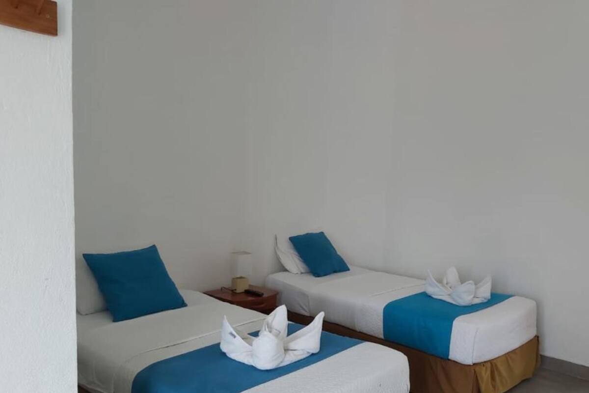 Two single beds with blue pillows and white towels folded on them.