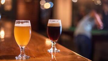Two glasses of beer on a bar counter.