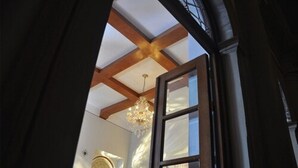 A room with a high ceiling, wooden beams, a chandelier, and a large window. - Gran Casa Sayula Hotel & Spa (Sayula)
