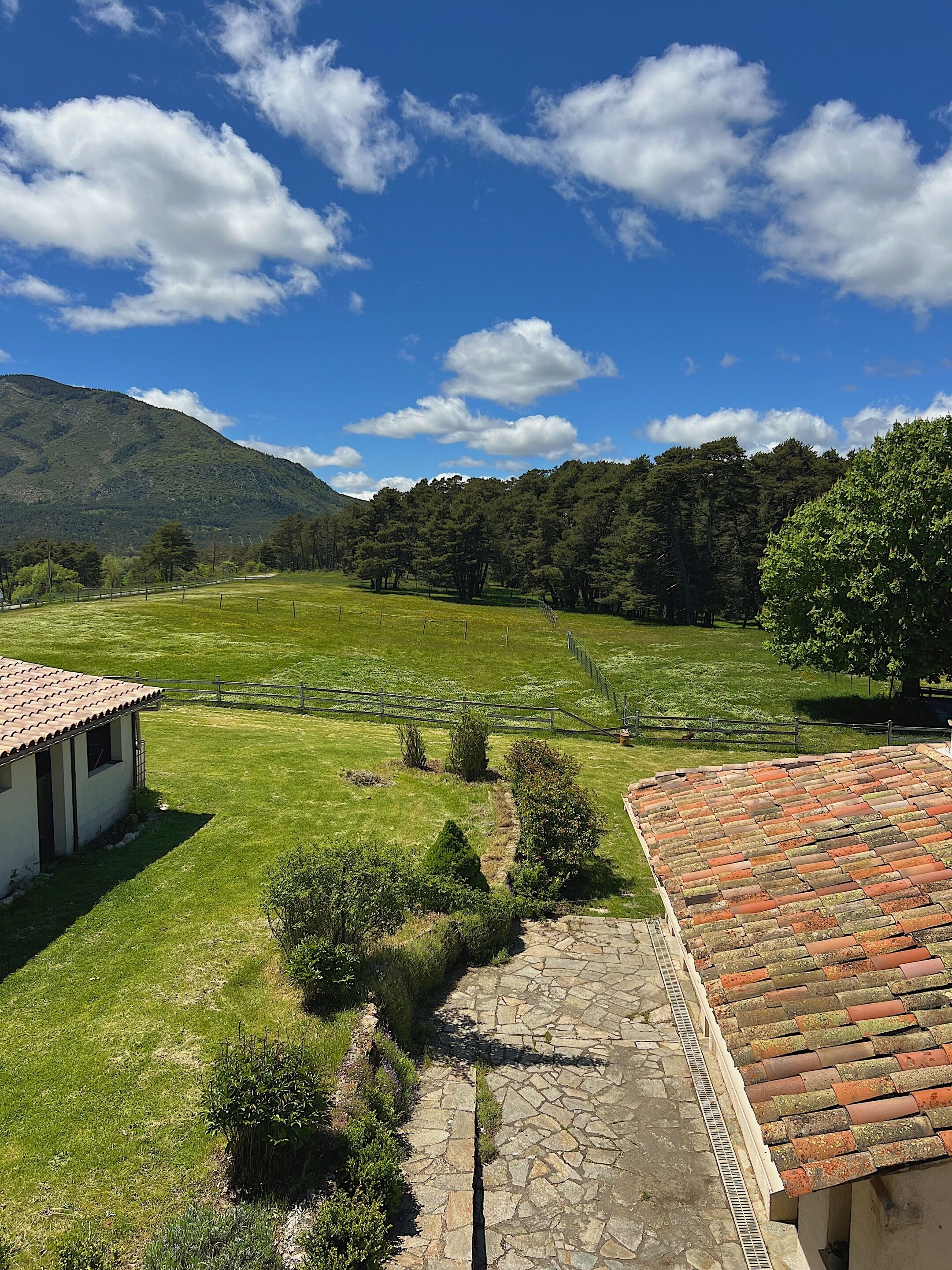 Paisaje rural con una casa, un sendero de piedra y un campo cercado.