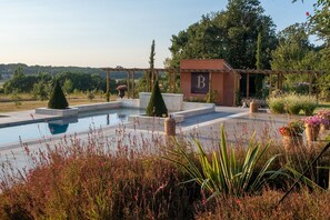 A pool area with a pergola, a small building with a 'B' logo, and surrounding greenery. - Domaine de Belair (Eaunes)