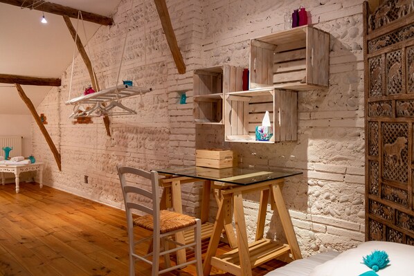A rustic room with exposed brick walls, wooden beams, a glass table, and a white chair. - Domaine de Belair (Eaunes)
