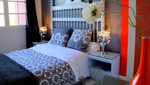 A bedroom with a bed, nightstands, a lamp, and a vase with flowers.
