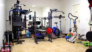 A gym with various exercise equipment, including a weight bench, a squat rack, and a treadmill.