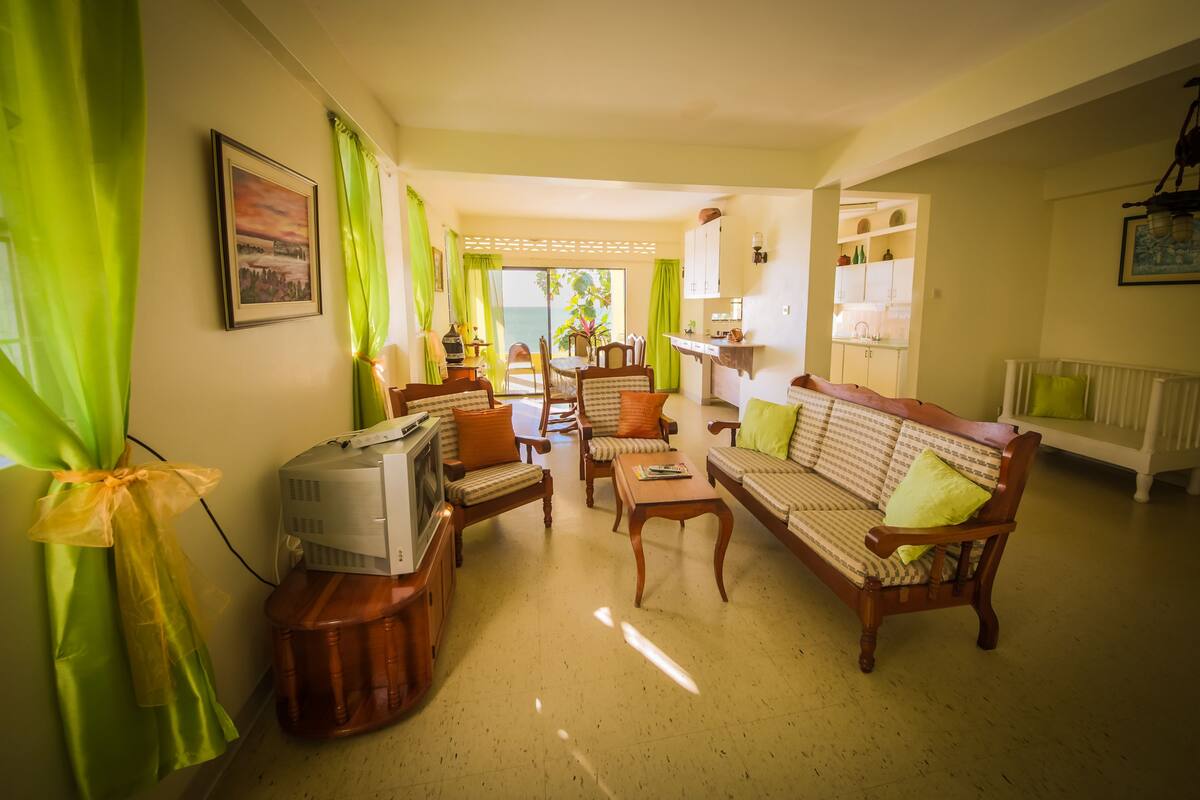 A living room with a TV, sofa, chairs, and a dining table.
